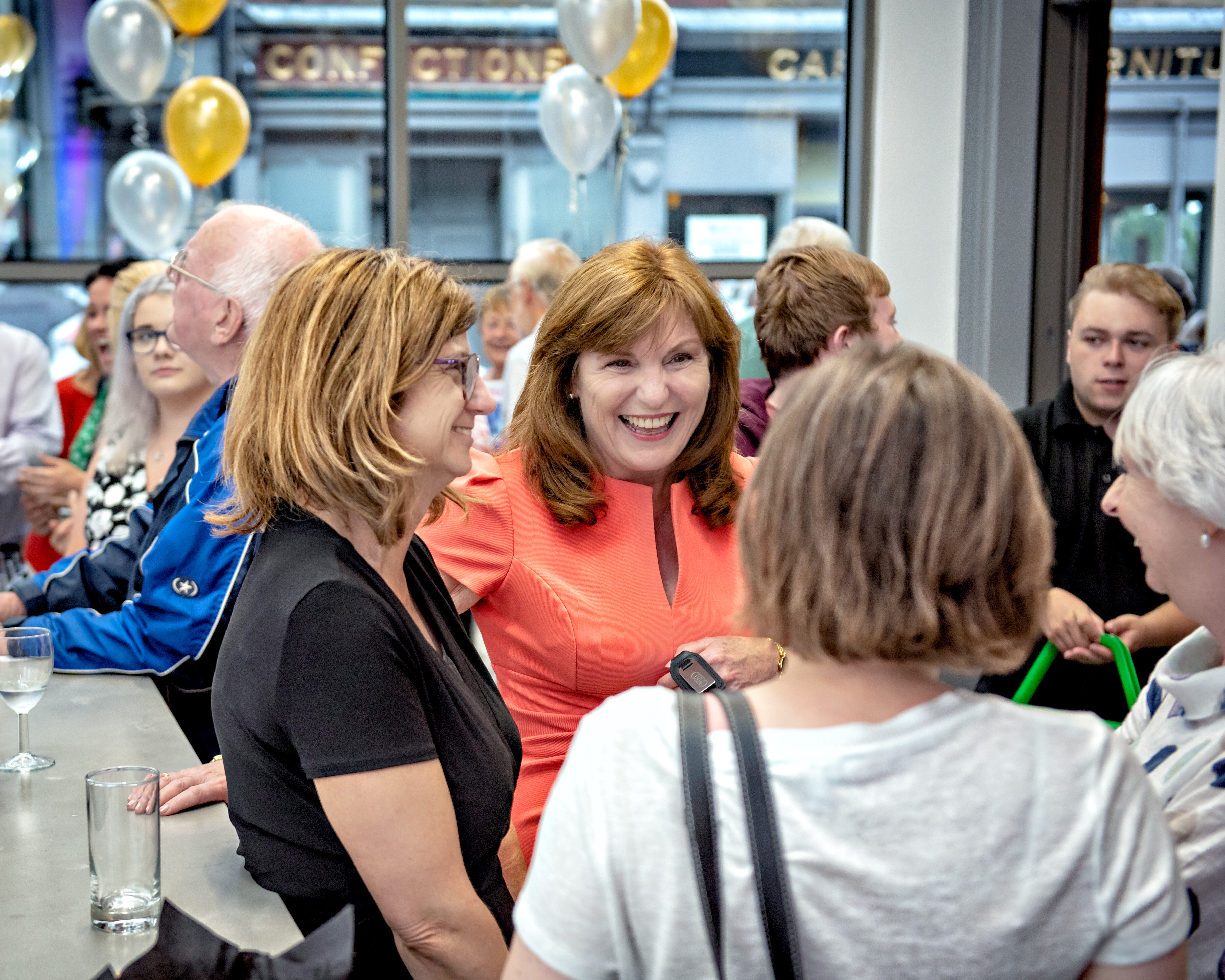 Image of guests mingling and laughing with balloons in the background