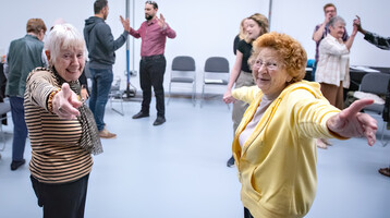 Photo of two workshop participants smiling and pointing towards the camera.