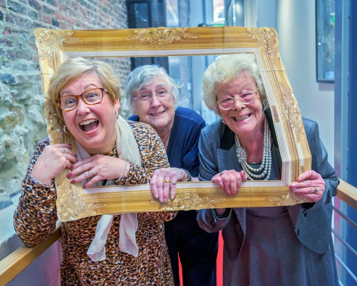 Image of three participants smiling holding picture frame prop.