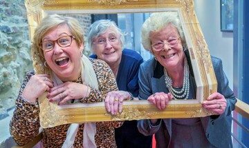 Image of three participants smiling holding picture frame prop.